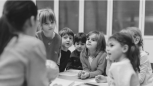 Niños poniendo atención a la explicación de la profesora (fotografía en blanco y negro)